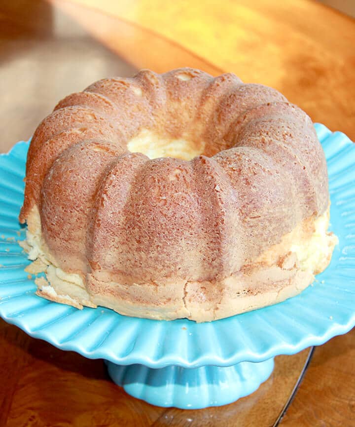 Whole baked Southern cream cheese pound cake on a blue cake stand.