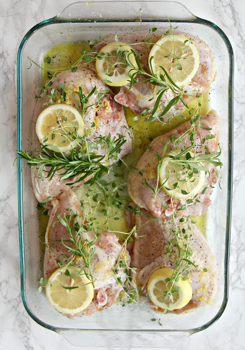Rosemary Lemon Chicken ready to bake with fresh herbs and lemon slices.
