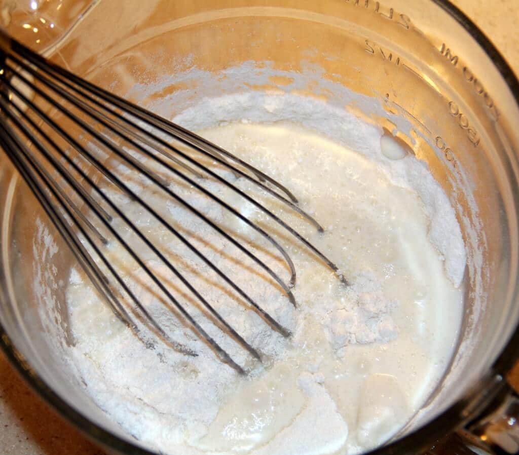 Whisking the batter for strawberry cobbler in a bowl. 