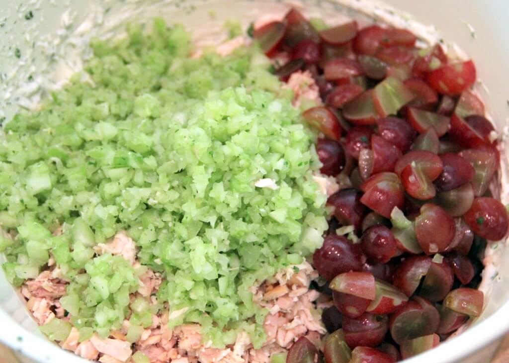 Chicken, celery, and grapes in a large bowl for chicken salad. 