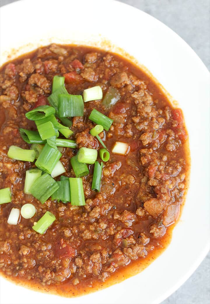 Overhead photo of a bowl of chili with green onions on top. 