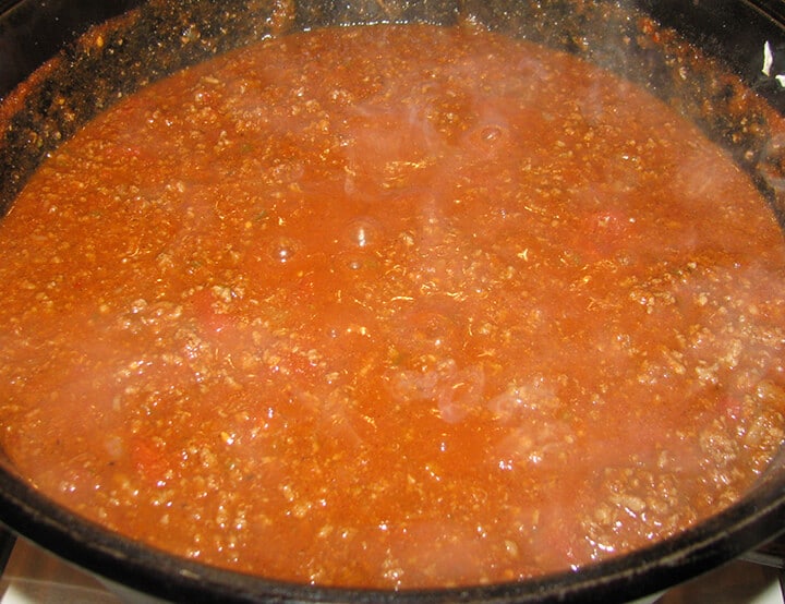 Chili recipe no beans simmering in a large pot on the stove.