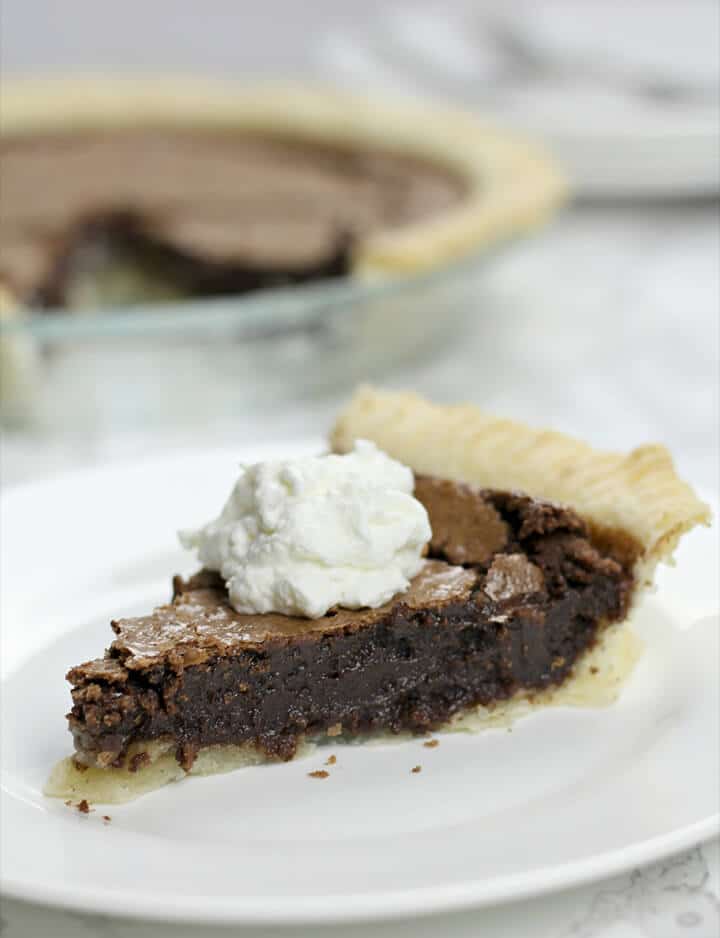 A slice of fudge pie topped with a dollop of whipped cream. 