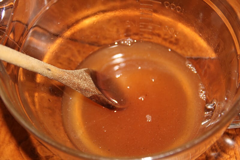 A bowl with sherry and honey and a wooden spoon stirring. 