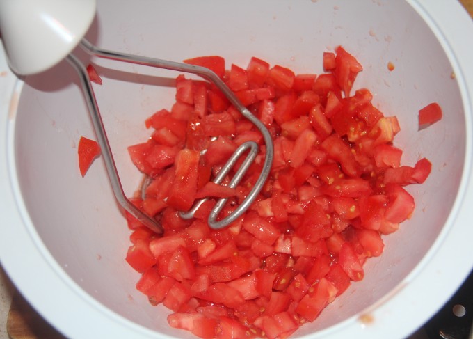 Mashing tomatoes to make fresh pasta sauce.