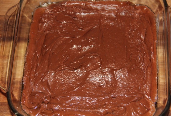 Spreading chocolate cobbler batter in the dish.