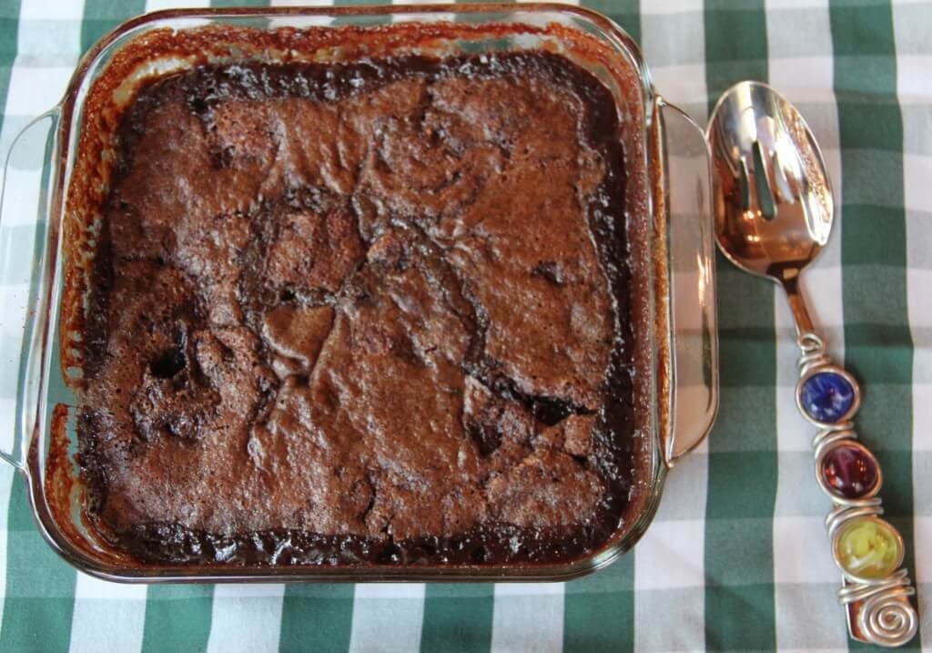 Finished chocolate cobbler in a dish with a spoon on the right. 