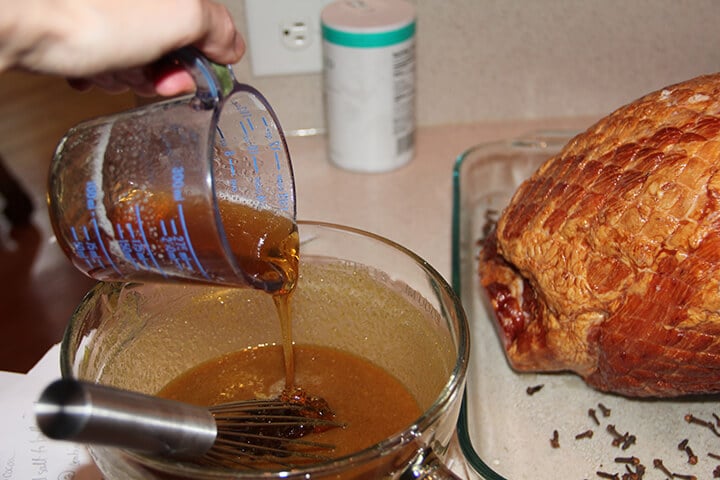 Pouring honey into bowl for baked ham.