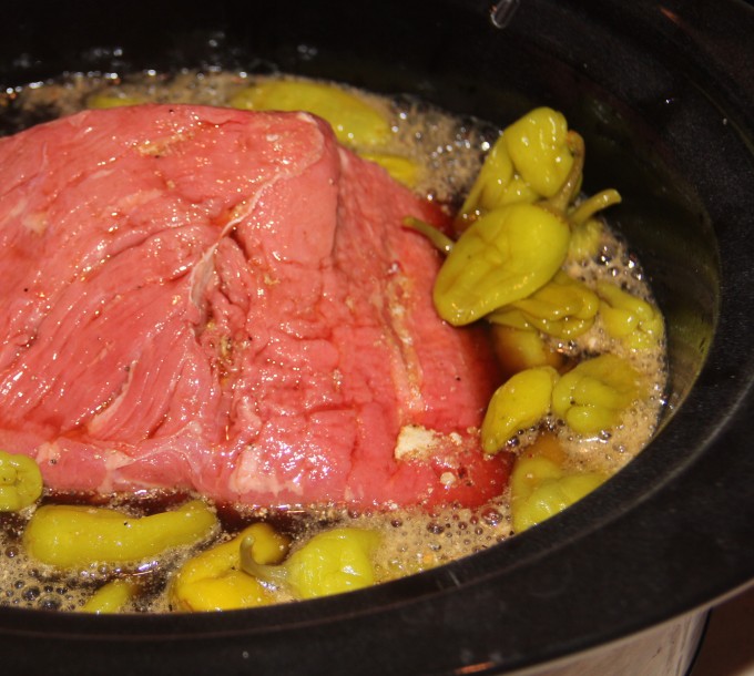 Putting roast and peppers in crockpot.