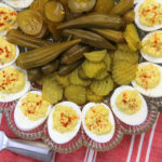 Closeup of Southern deviled eggs on a platter with pickles in the center.