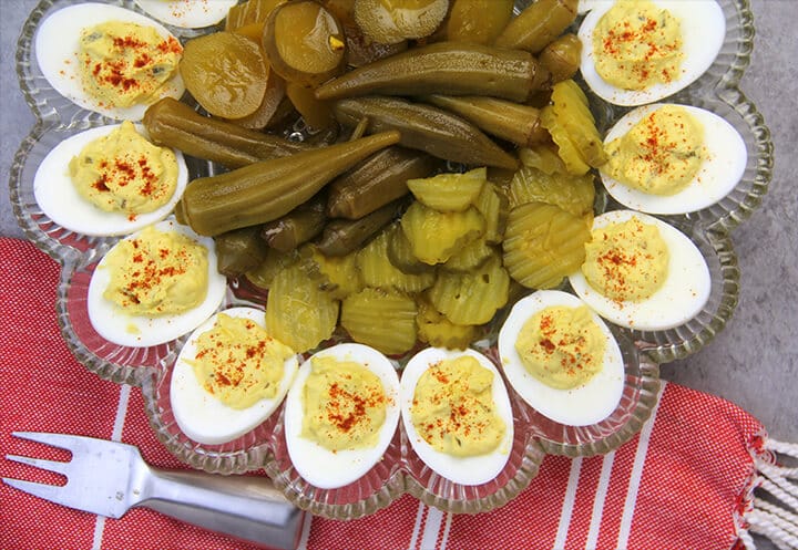 Closeup of Southern deviled eggs on a platter with pickles in the center.