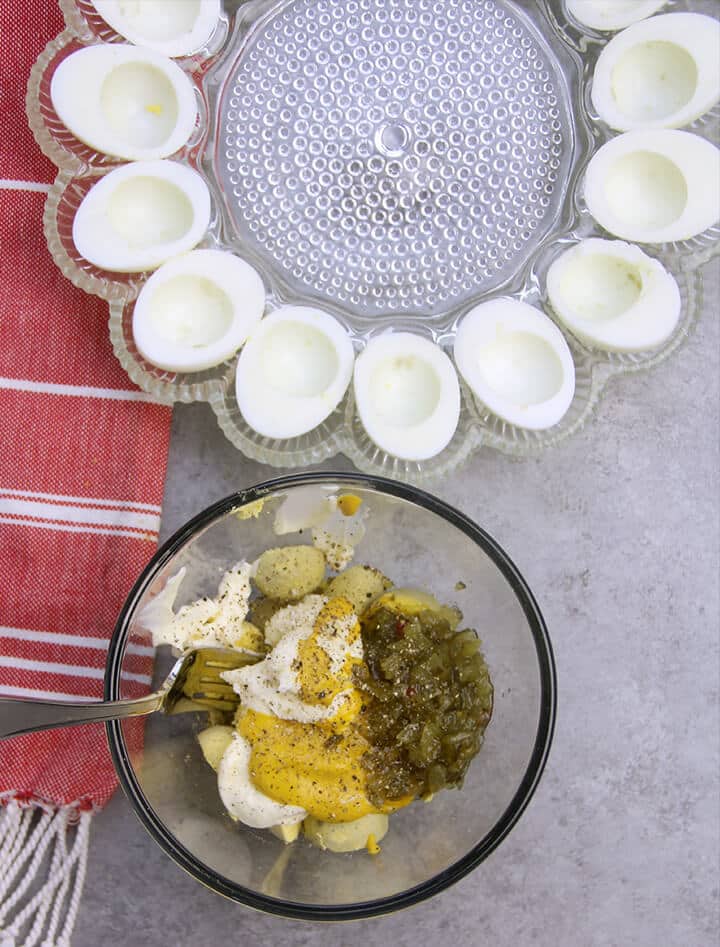 Mayonnaise, mustard, pickles, and egg yolks in a bowl to make deviled eggs.