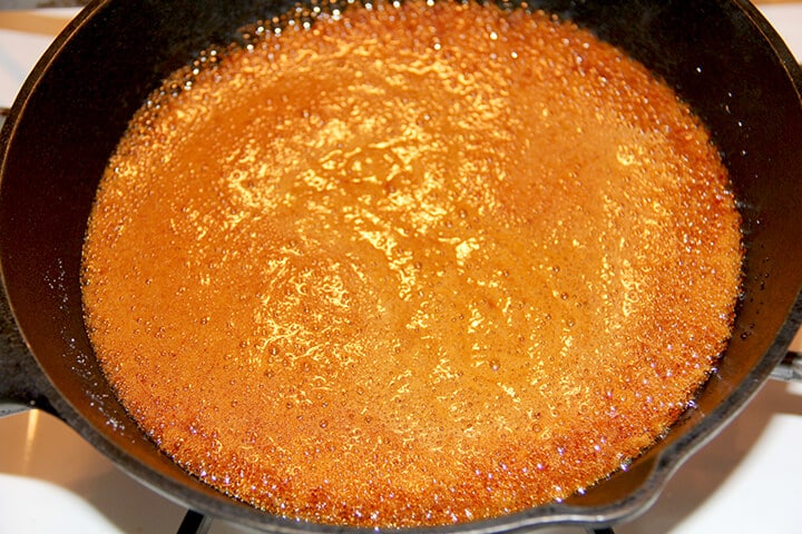 Dark amber caramel syrup in skillet for caramel icing.
