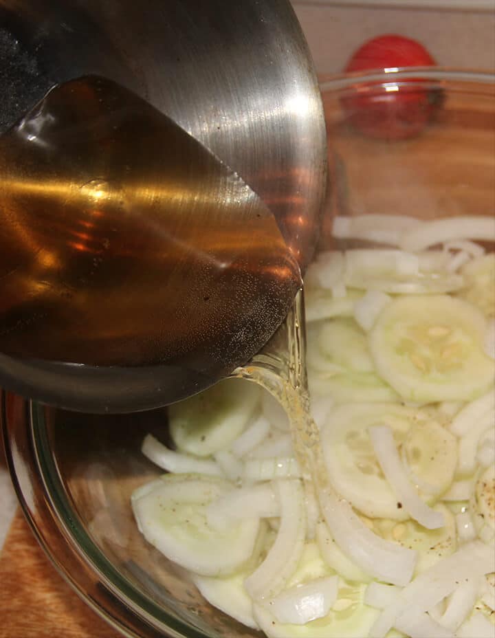 Pouring vinegar over cucumbers and onions.