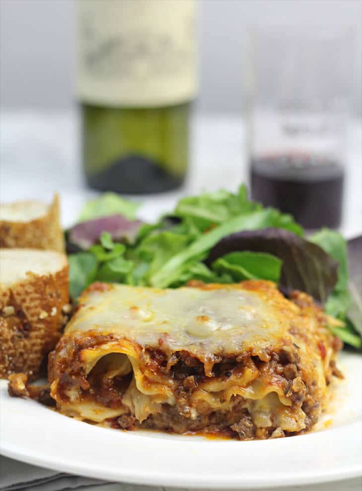 Serving of lasagna without ricotta on a plate with salad.