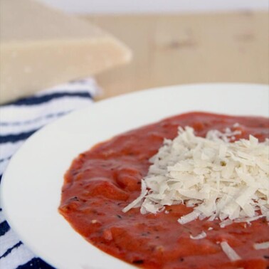 Tomato soup in a bowl with grated cheese on top.