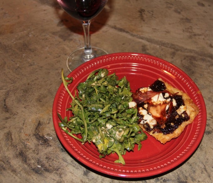 plate with slice of fig jam pizza and arugula salad