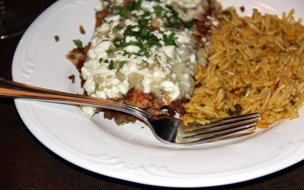Beef enchilada on a plate with rice and a fork.