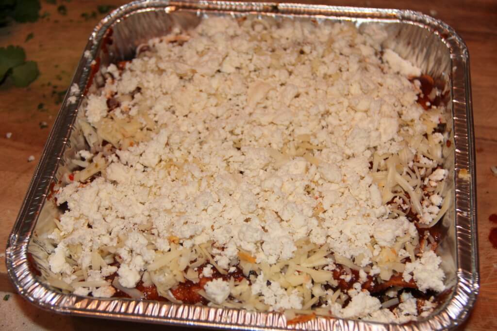 A pan of beef enchiladas with crumbled cheese.