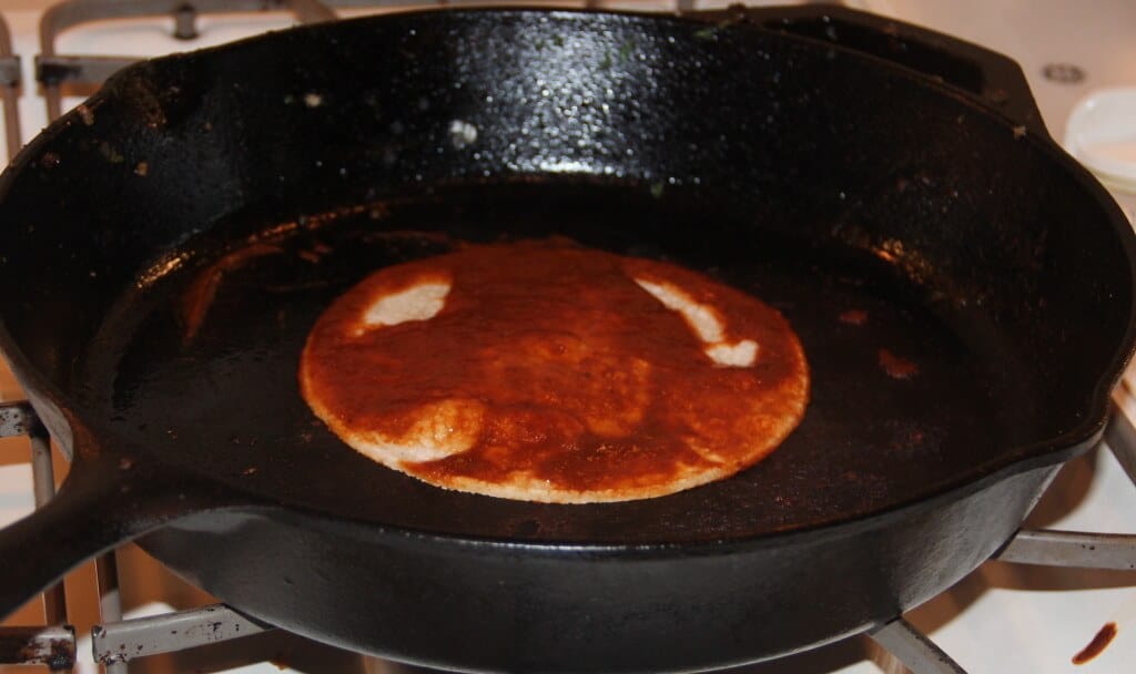 Heating tortilla in a cast iron skillet.