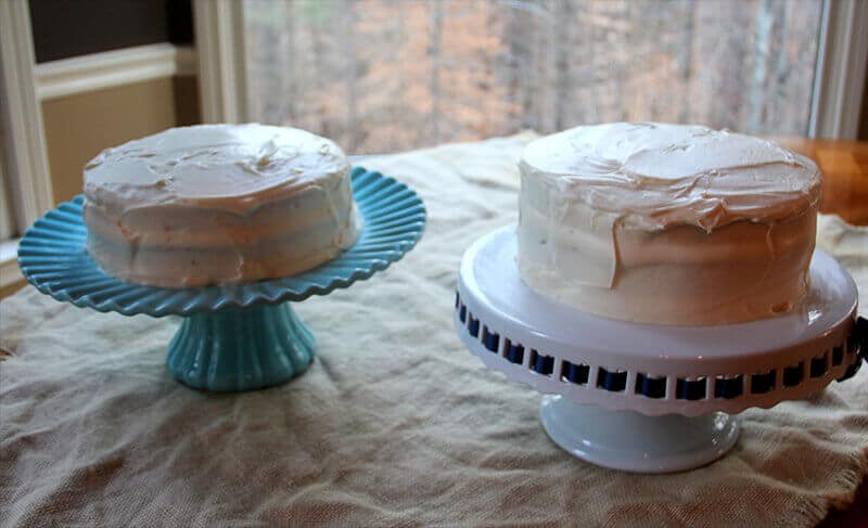 Two red velvet cakes side by side on cake stands. 