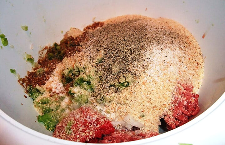 Mixing breadcrumbs, ground beef, and seasonings in a bowl for meatloaf muffins.