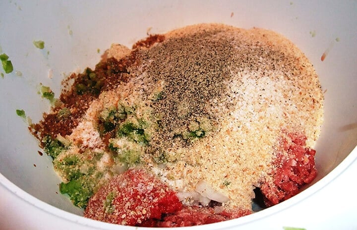 Mixing breadcrumbs, ground beef, and seasonings in a bowl for meatloaf muffins.