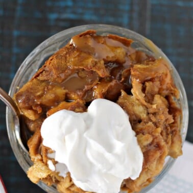 Overhead shot of a serving of pumpkin bread pudding in a dish with whipped cream.