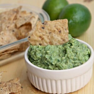 White bowl filled with guacamole and chips.