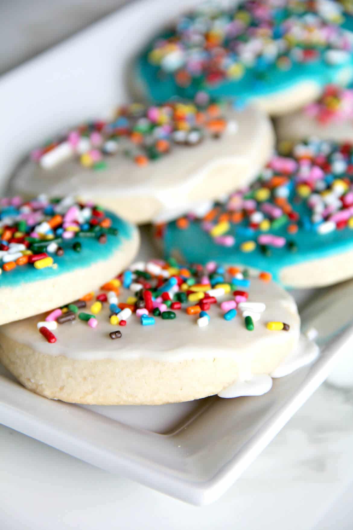 A delicious and easy sugar cookie recipe with simple icing that's quick and easy to apply. And sprinkles, of course! Kids love these cookies.