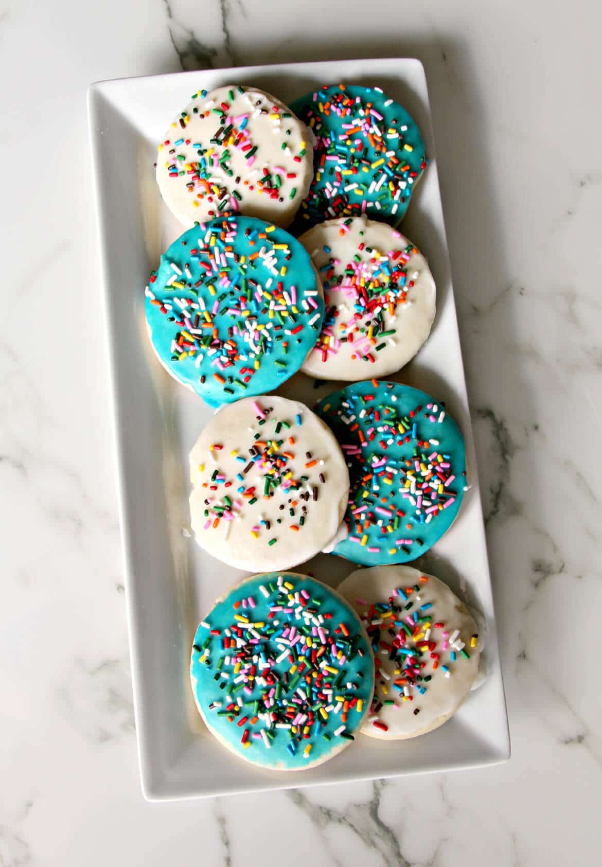 A delicious and easy sugar cookie recipe with simple icing that's quick and easy to apply. And sprinkles, of course! Kids love these cookies.