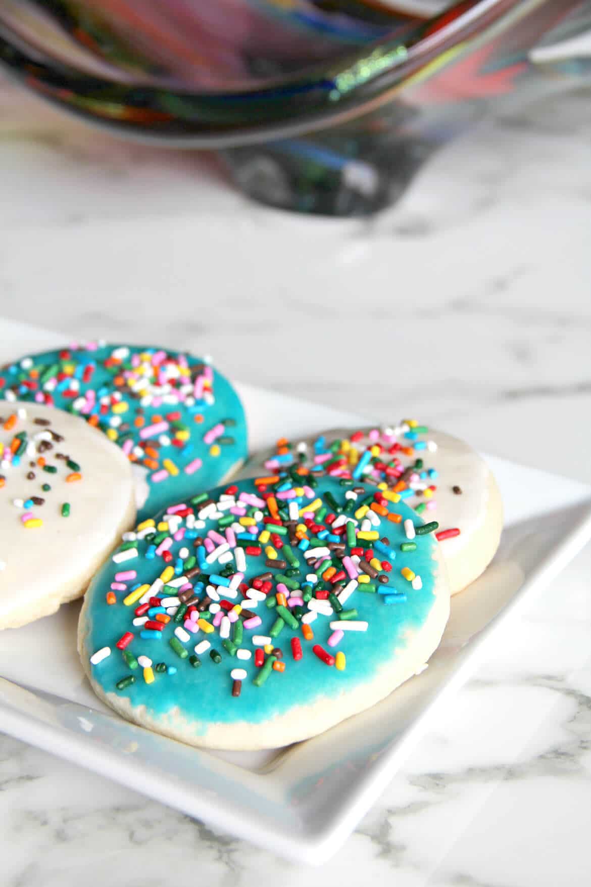 A delicious and easy sugar cookie recipe with simple icing that's quick and easy to apply. And sprinkles, of course! Kids love these cookies.