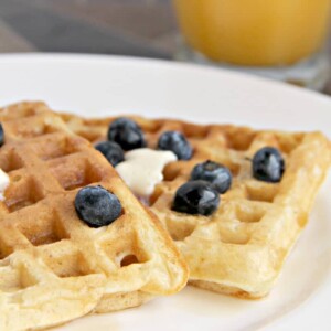 Two homemade buttermilk waffles with blueberries on a plate.