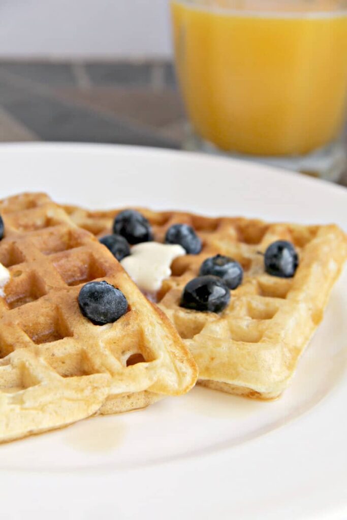 Two homemade buttermilk waffles with blueberries on a plate. 