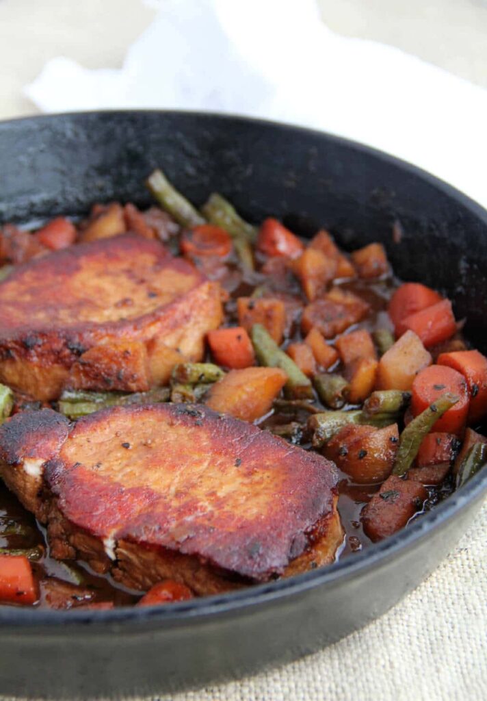 A pan filled with meat and vegetables, with Pork Chop.