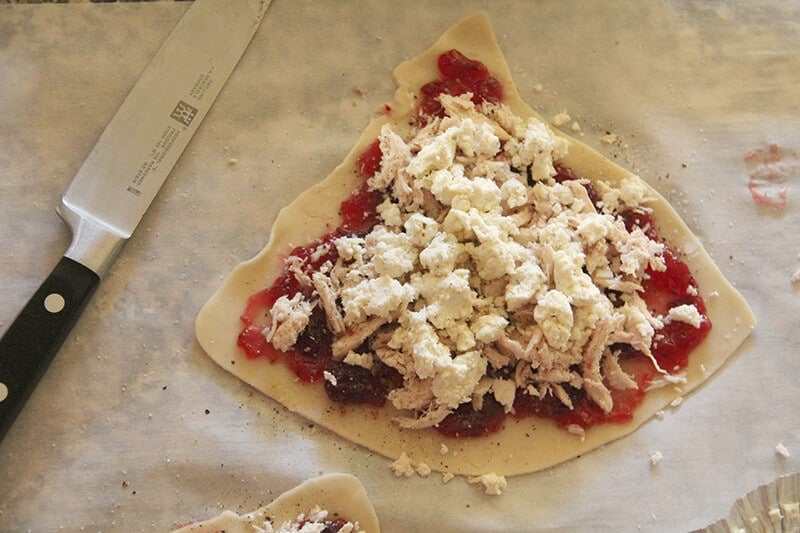 Overhead shot of Boursin cheese on top of turkey on top of cranberry sauce on pie dough. 