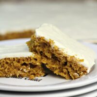 Two pieces of pumpkin sheet cake on a plate.
