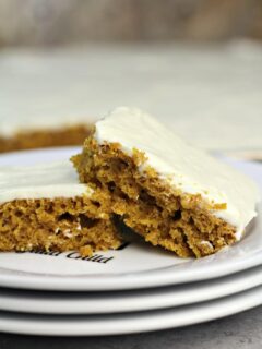 Two pieces of pumpkin sheet cake on a plate.