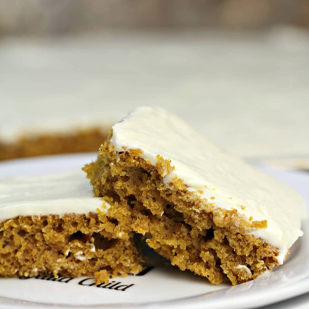 Pumpkin sheet cake with cream cheese frosting on a plate.