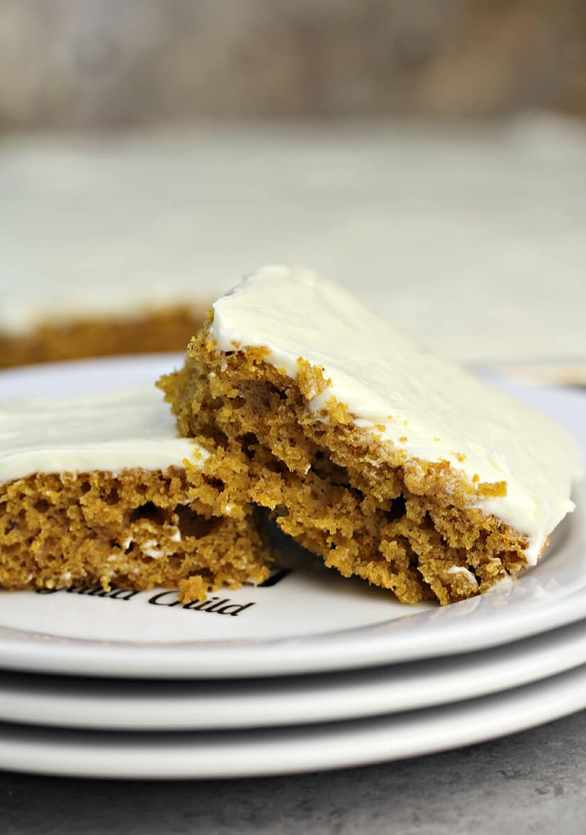 Two pieces of pumpkin sheet cake on a plate.