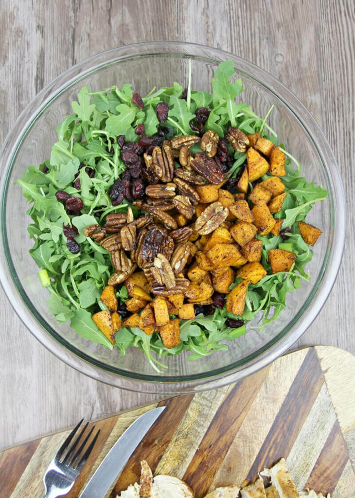 Arugula Salad in bowl with sweet potatoes and pecans.