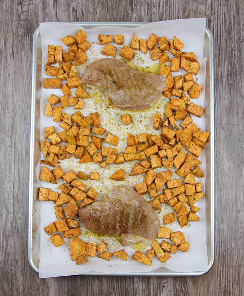 Arugula salad with roasted sweet potatoes, chicken on a baking sheet.