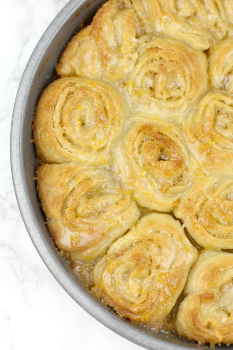 Baked orange rolls in a cake pan.