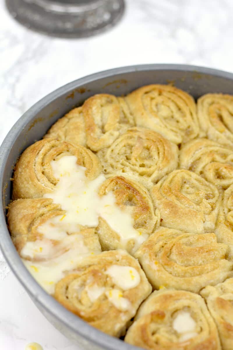 Powdered sugar glaze over orange rolls.