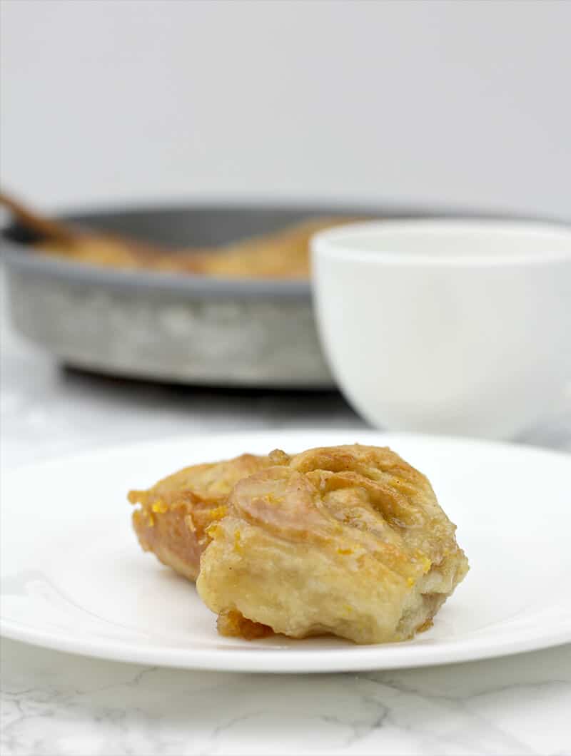 Plate of orange rolls with coffee.