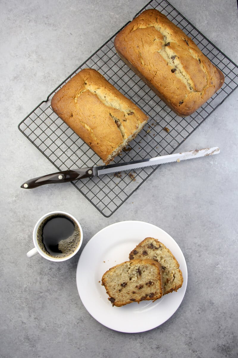 Slices of Chocolate Chip Banana Bread and two loaves with a cup of coffee. 