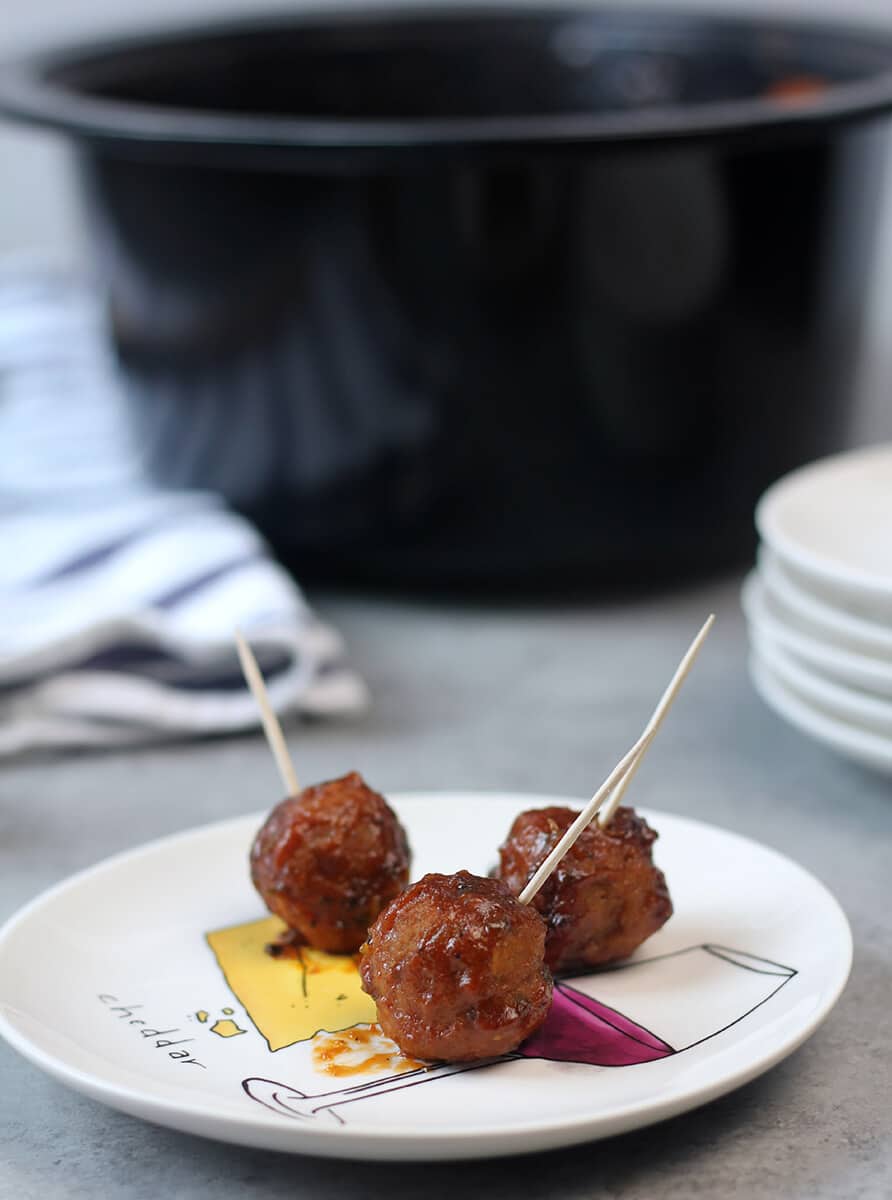 Plate of meatballs with crockpot in the background.