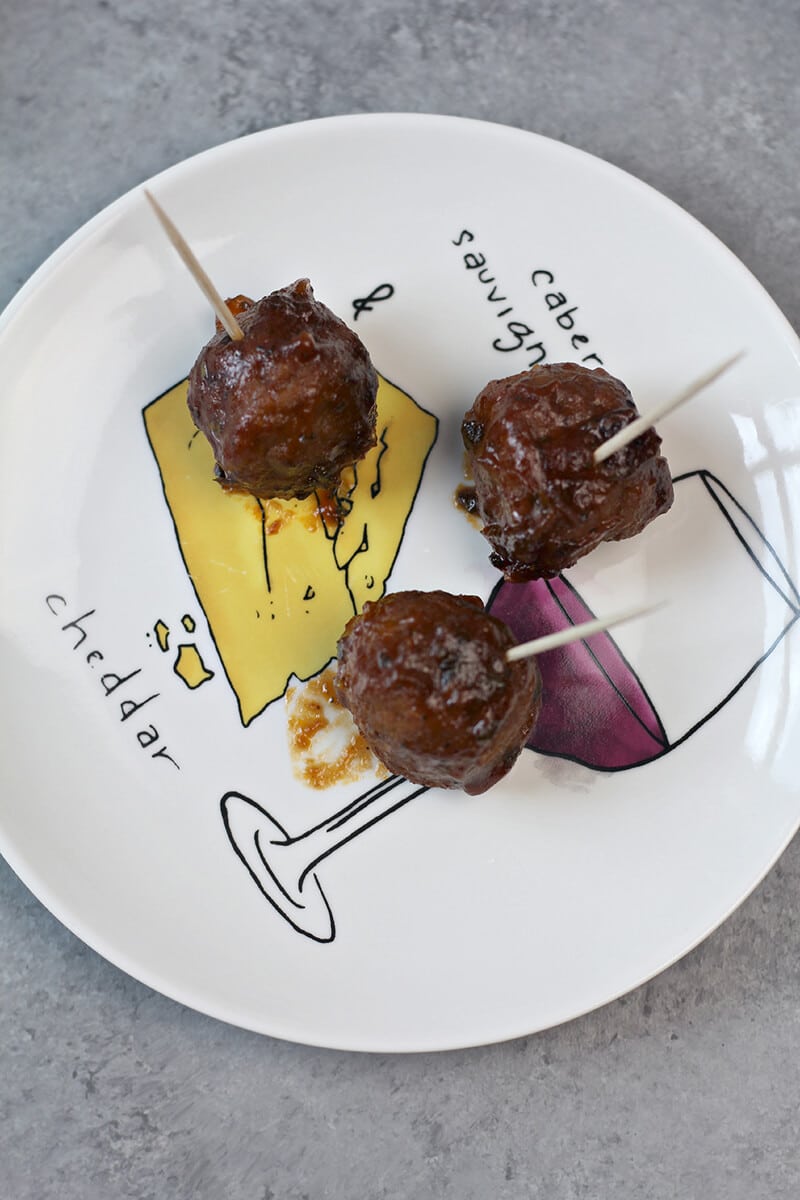 Overhead view of three slow cooker barbecue meatballs on a plate.