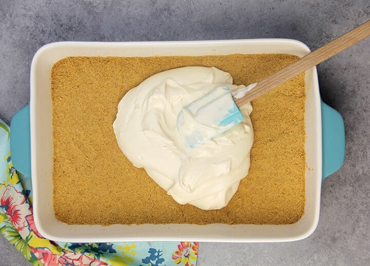 Cream cheese filling spread on graham cracker crust for cream cheese banana pudding.