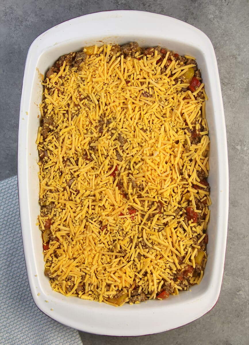 The mixture of meat, farro, and peppers topped with cheese in a baking dish for unstuffed pepper casserole.